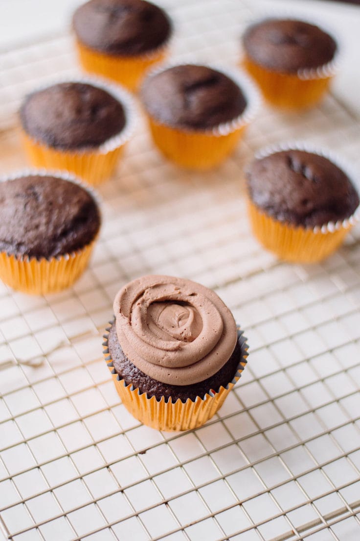 Piping chocolate frosting on a cupcake.