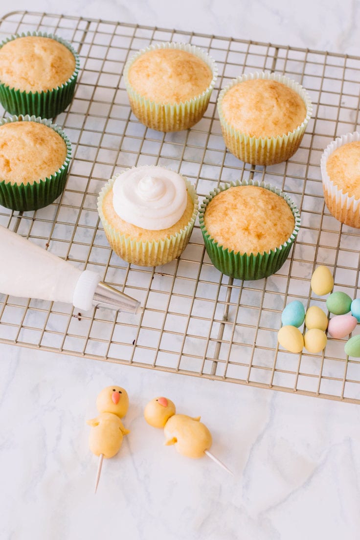 A cupcake with an easter chick made of fondant and candy eggs for the cutest Easter dessert.