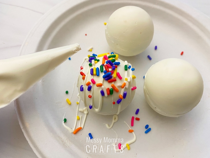 White chocolate spheres with rainbow sprinkles added to the top of one.