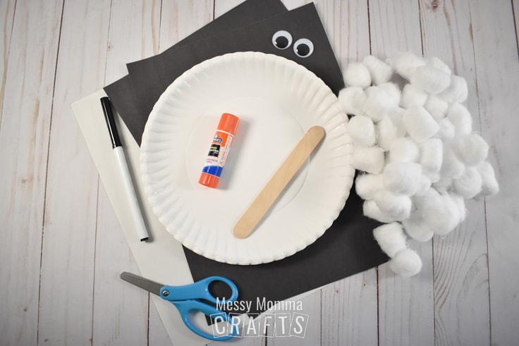 Glue stick, craft stick, marker, scissors, paper plate, and cotton balls.