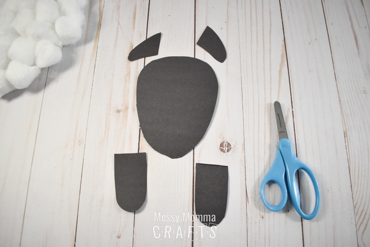 Scissors and black construction paper sheep feet and facial features.