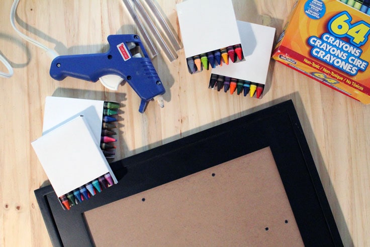 Hot glue gun and glue sticks, boxes of crayons, and an empty black picture frame.