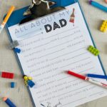 Blue clipboard with a fill in the blank Father's Day worksheet attached, surrounded by legos, darts & markers.