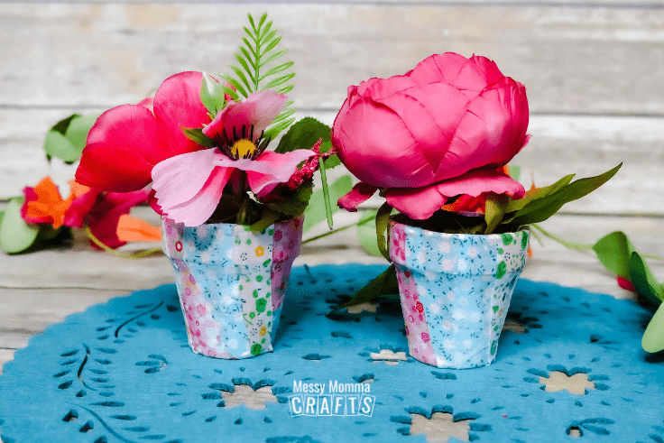 Two embellished flower pots filled with tropical silk flowers.