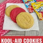 Colorful Kool-Aid cookies with Kool-Aid mix on a wood background.