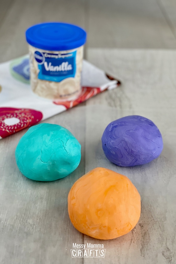 Three balls of colorful edible play dough with a can of frosting in the background.