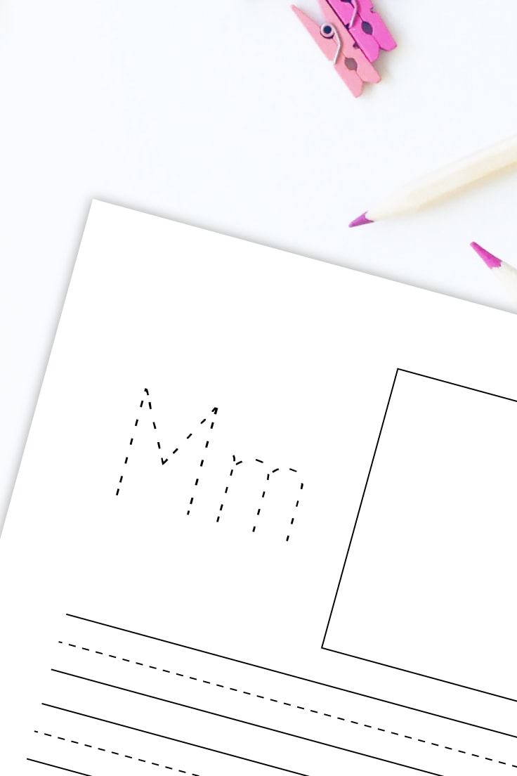 Preview of letter M printable PDF with colored pencils and clips on white desk.