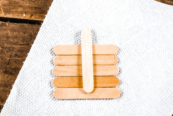 Laying popsicle sticks out in the shape of a square pumpkin