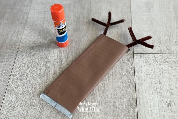 Reindeer Candy Bar sealed with a glue stick on a wood background.