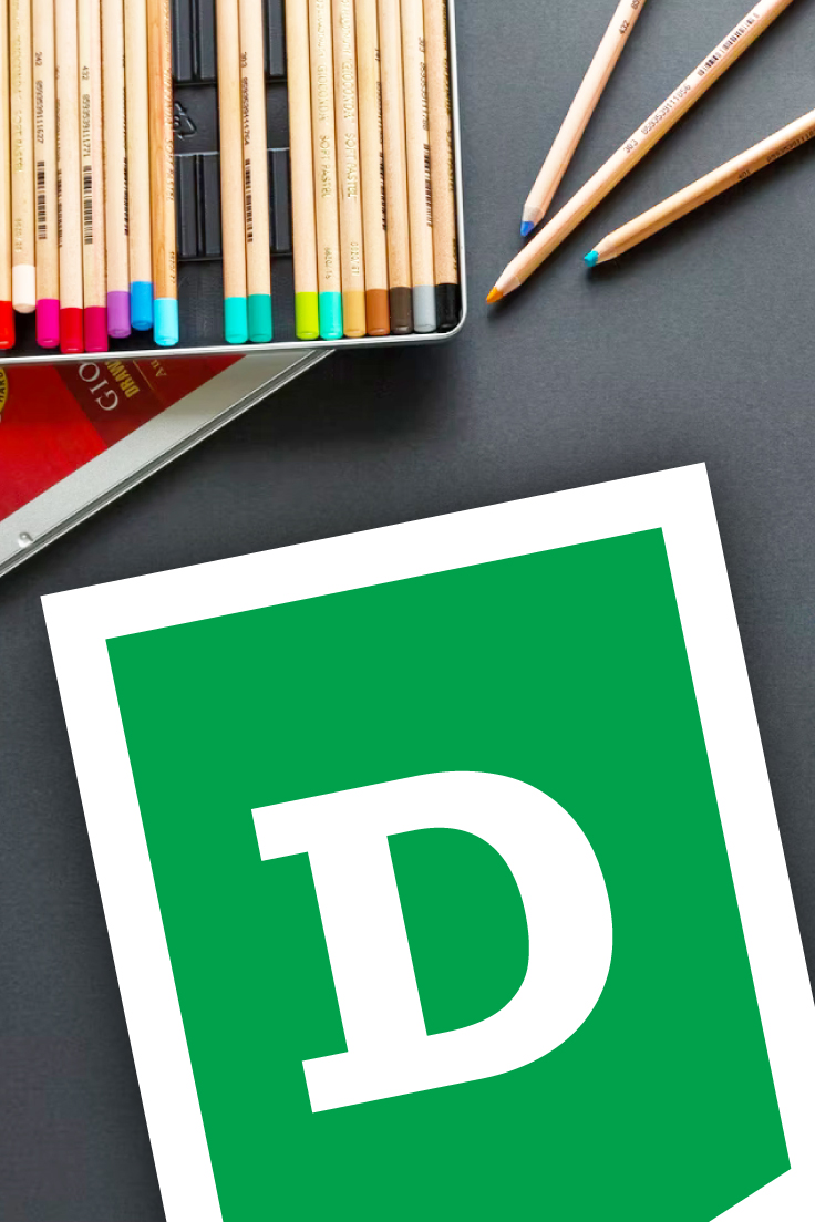 Preview of letter D page of alphabet letter banner printable on black desktop with set of colored pencils showing.