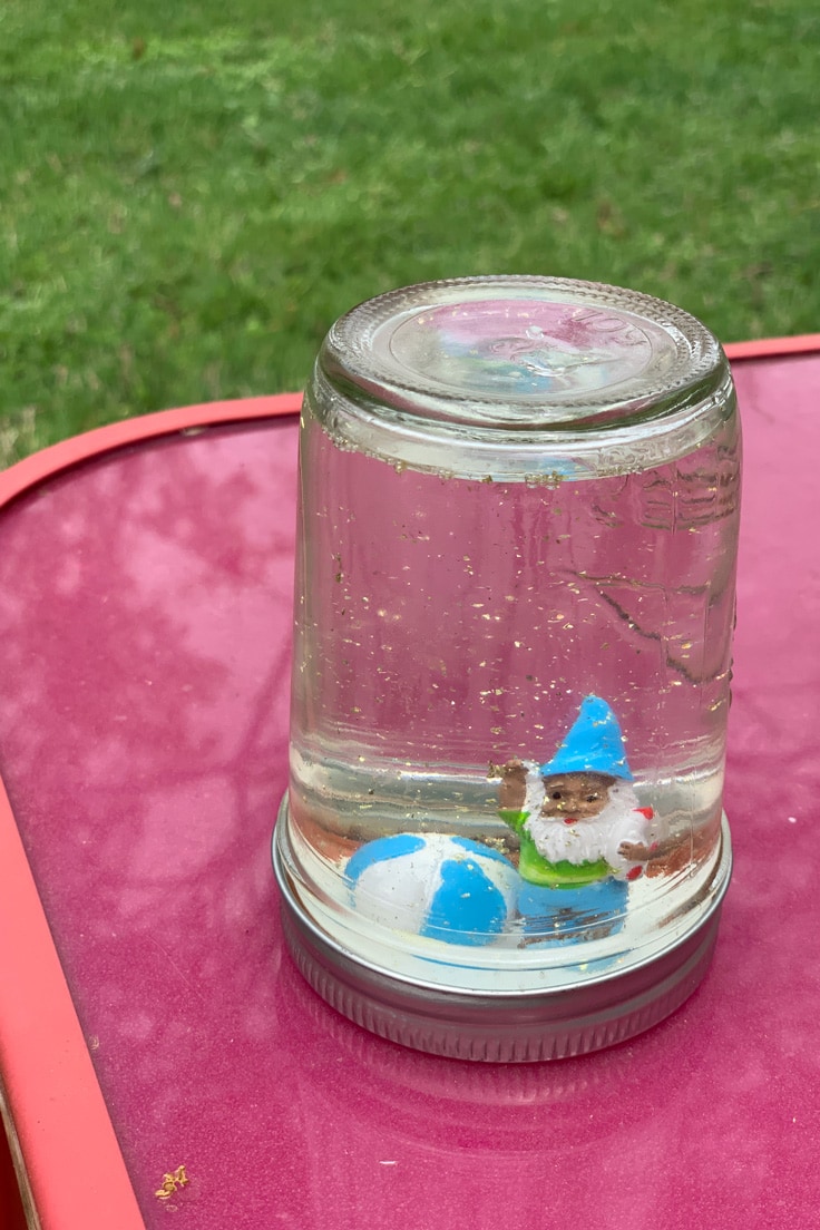 Upside-down canning jar with a gnome, beach ball, and glitter inside.