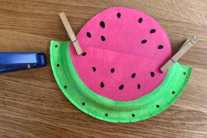 Paper watermelon clipped together with clothespins to punch holes.