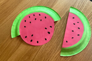 Paper plates painted green around the edge and pink in the center with black dots.