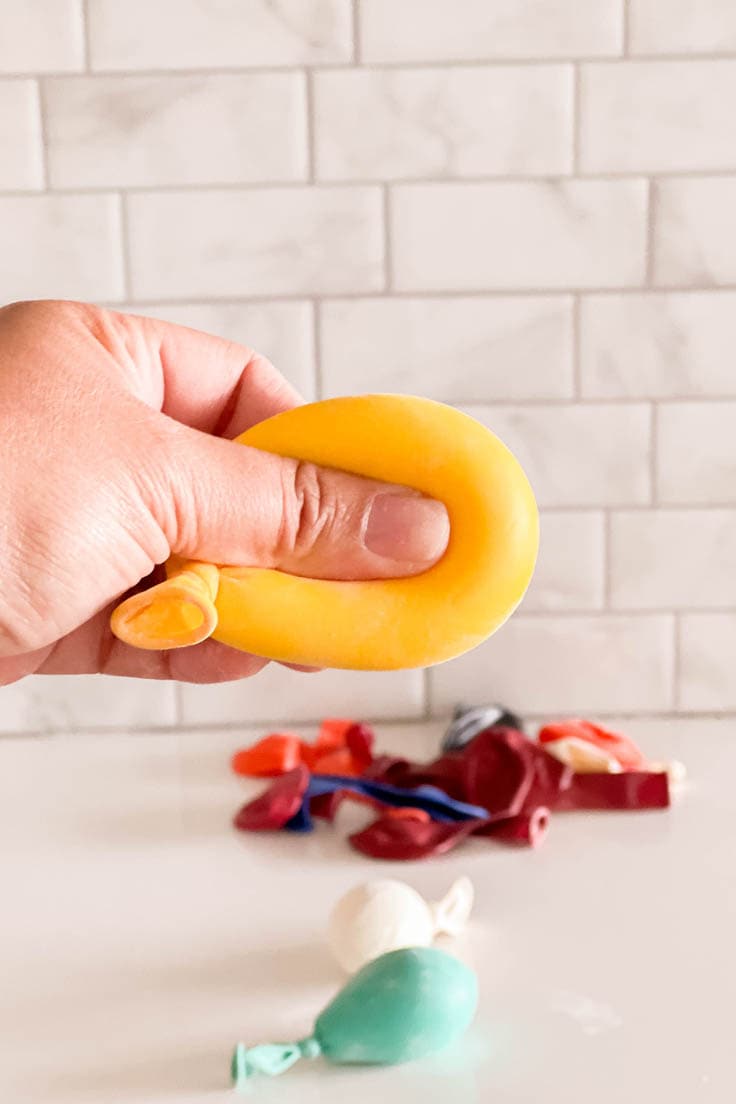 A hand pressing into a homemade yellow balloon stress ball