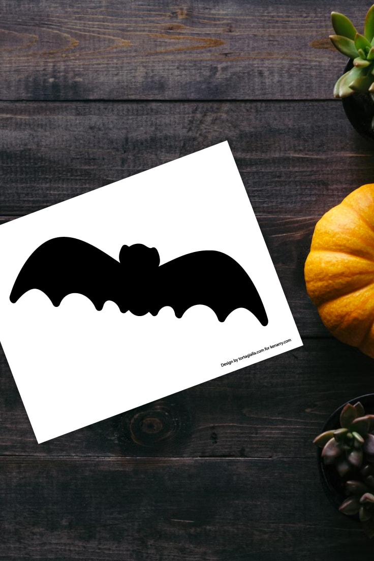 Preview of bat silhouette stencil on dark wooden background with pumpkin on the right.