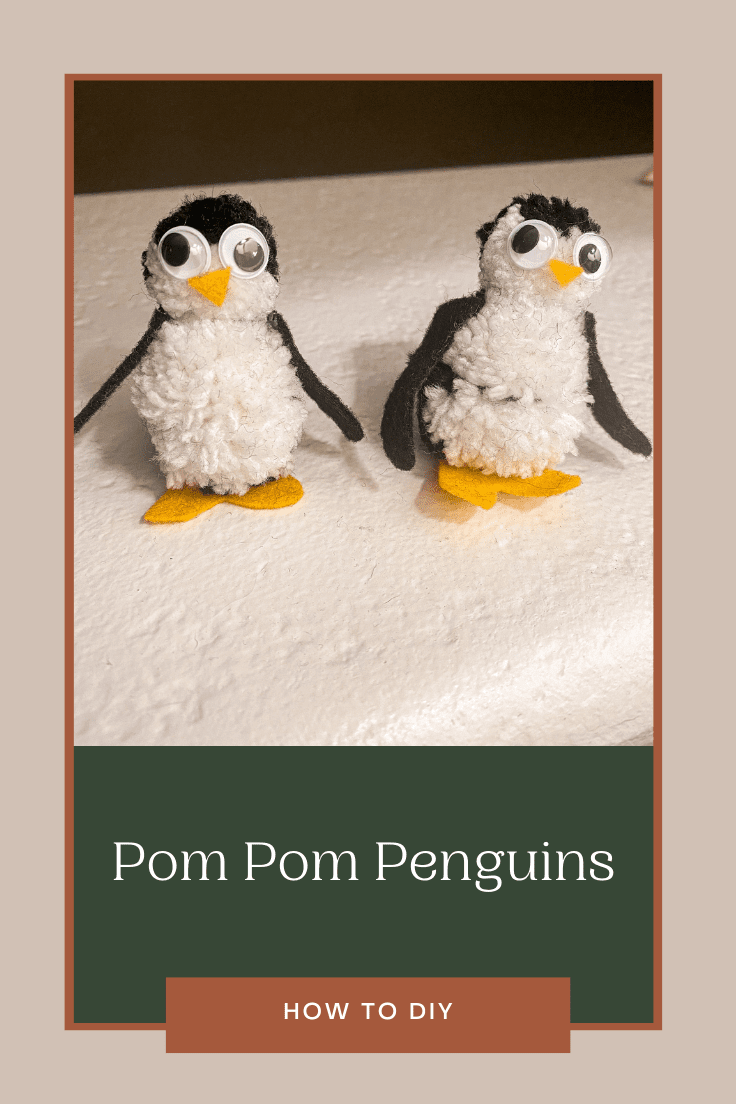Two pom pom penguins standing next to one another with googly eyes, wings, a triangle yellow felt nose, and yellow feet.