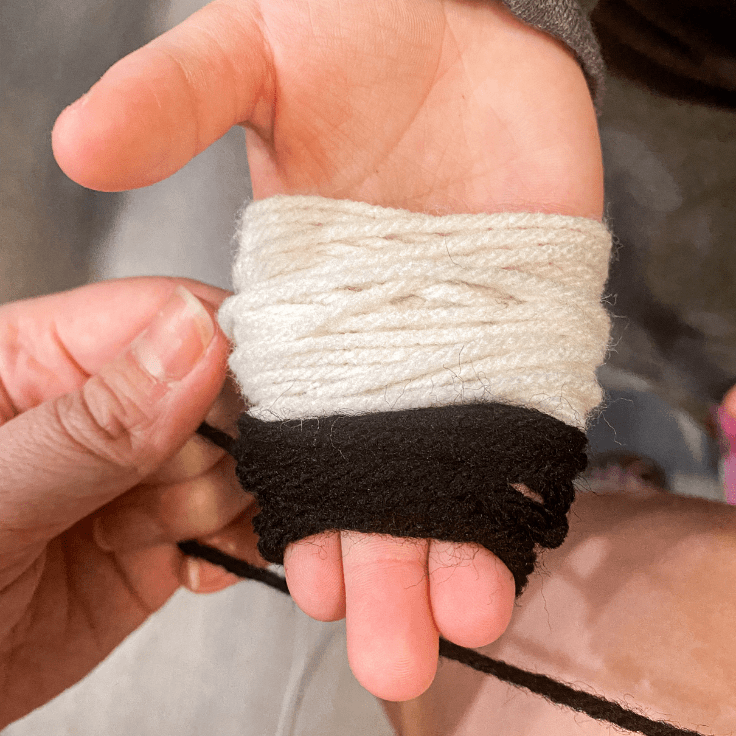 white and black yarn wrapped around a childs hand