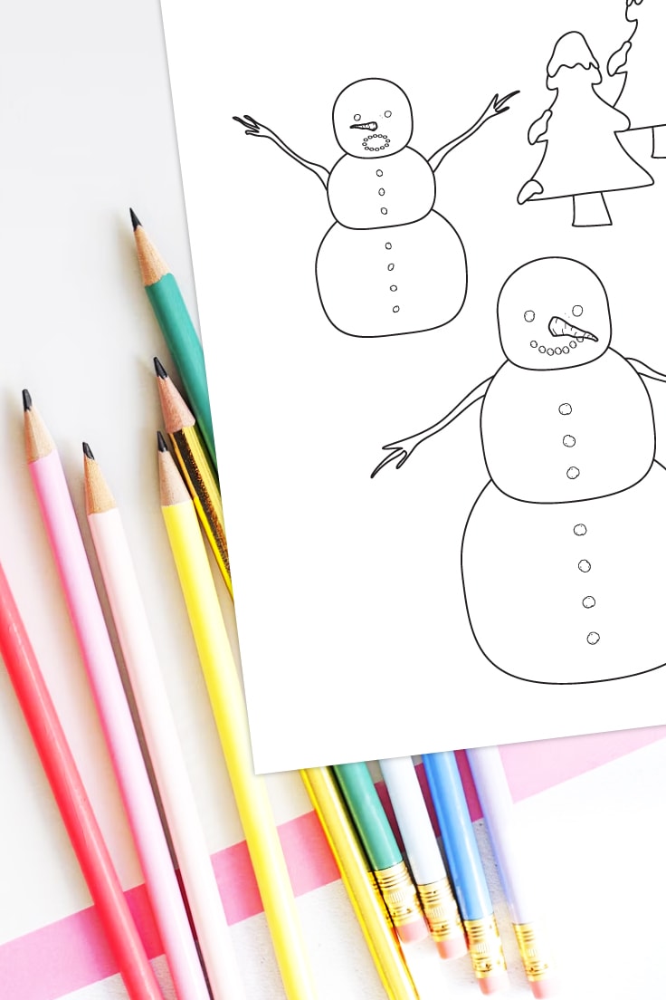 Preview of a snowmen with winter trees coloring page on white desk with assorted pencils underneath and on the left. 