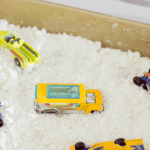 A closeup of a mini toy bus, sitting in DIY fake snow