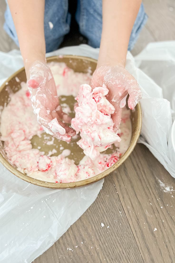White oobleck slime, with hints of red from its peppermint candy garnish