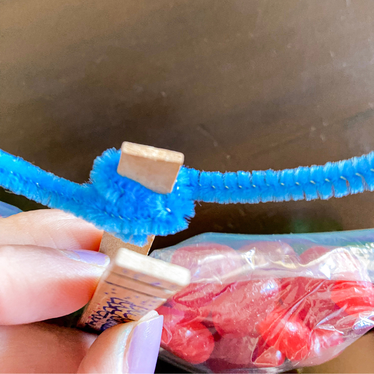 Close up of blue pipe cleaner wrapped around a clothes pin