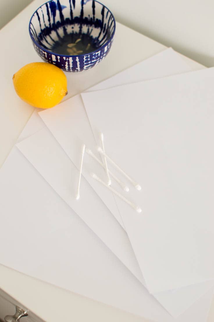 Q-tips sitting on white printer paper, ready to be used to outline some invisible ink using lemon juice
