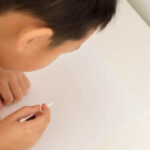 A young boy writes a secret message using invisible ink and a qtip