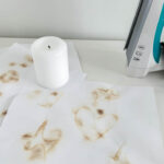 Designs and messages revealed on white printing paper, with a candle and clothes iron sit in the background