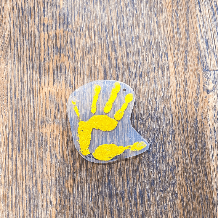 Yellow Shrinky Dink handprint with a hole at the top for a keychain