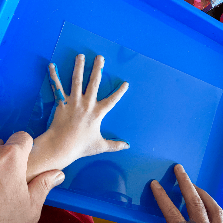 child putting a handprint on shrinky dink
