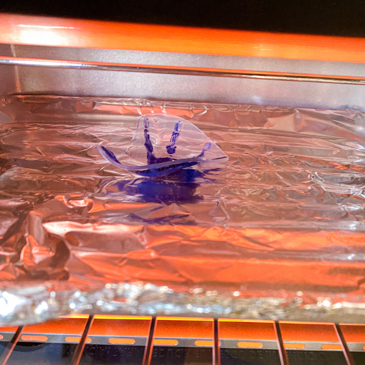 Blue shrinky dink handprint in the oven curling