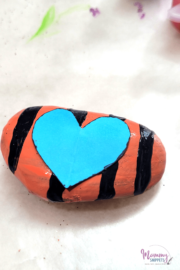 Child painting a Friendship Rock using a heart template