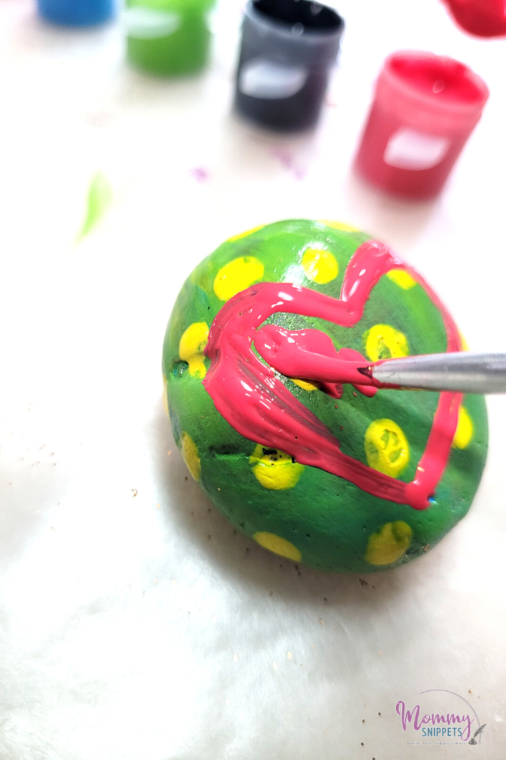 Child painting a heart on a Friendship Rock 