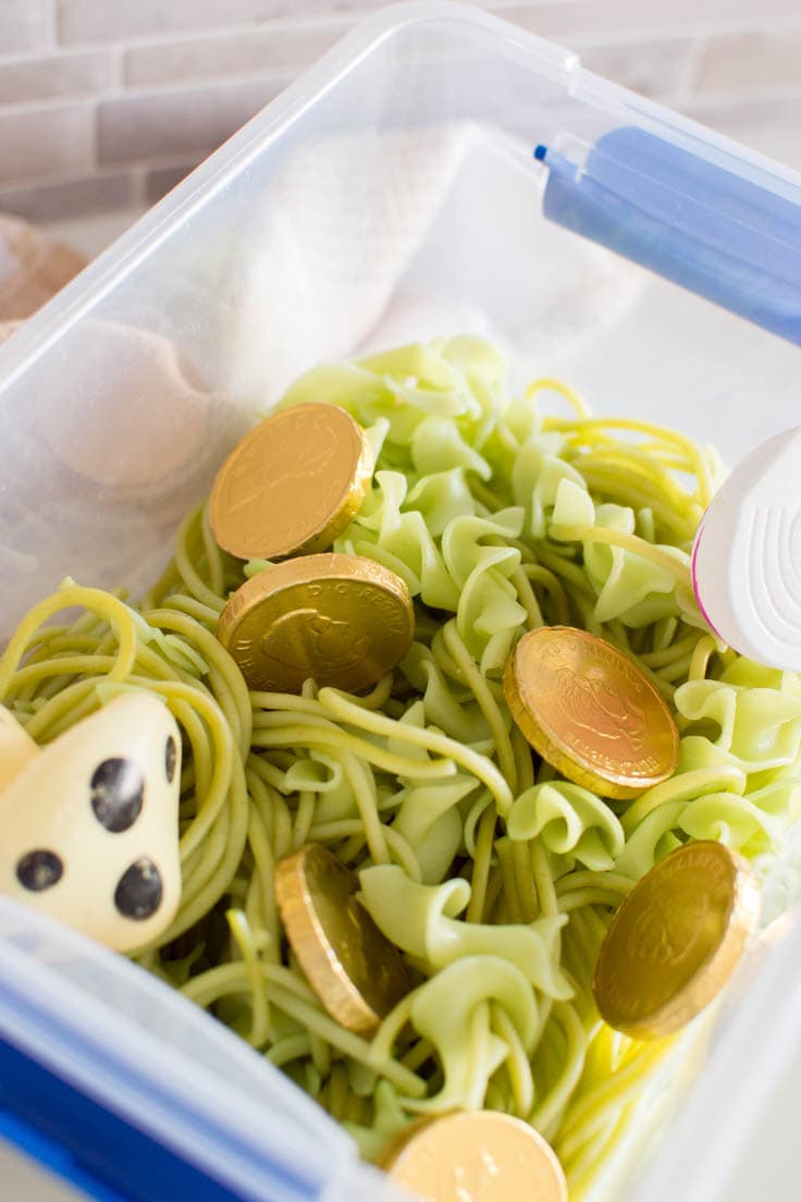 A small plastic bin filled with green pasta and toys