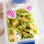 Aerial view of a small plastic bin filled with green pasta and toys
