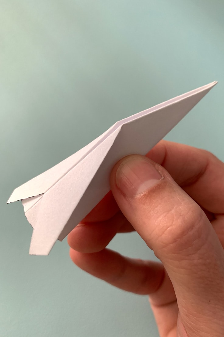A paper airplane folded to be long and narrow like a jet fighter.