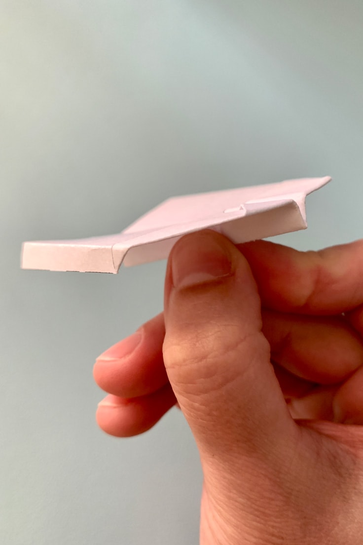 Closeup of a paper glider with side flaps.