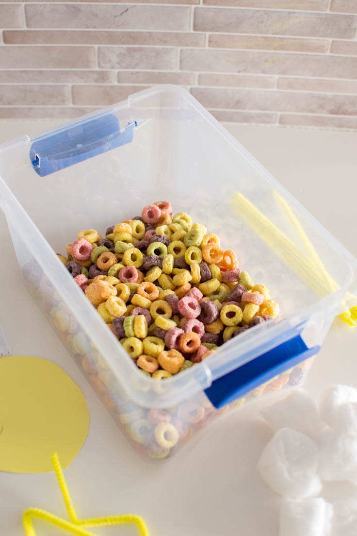 Adding Froot Loops to a small plastic bin