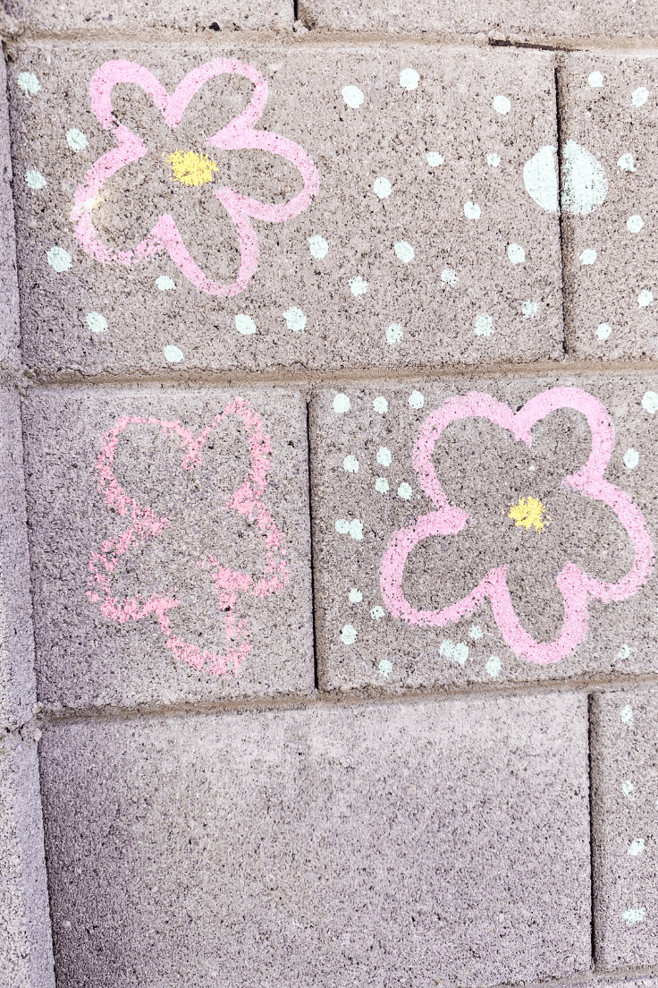 Flowers and dots drawn on a wall with chalk paint and a flower drawn with regular chalk to show the difference