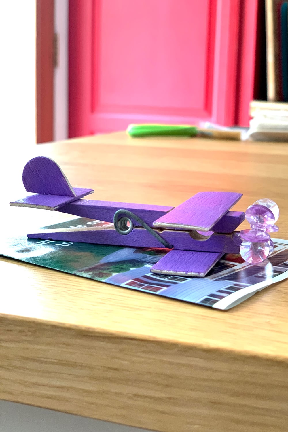 Side view of an assembled purple airplane with wings, a tail, rudder, and bead propeller.