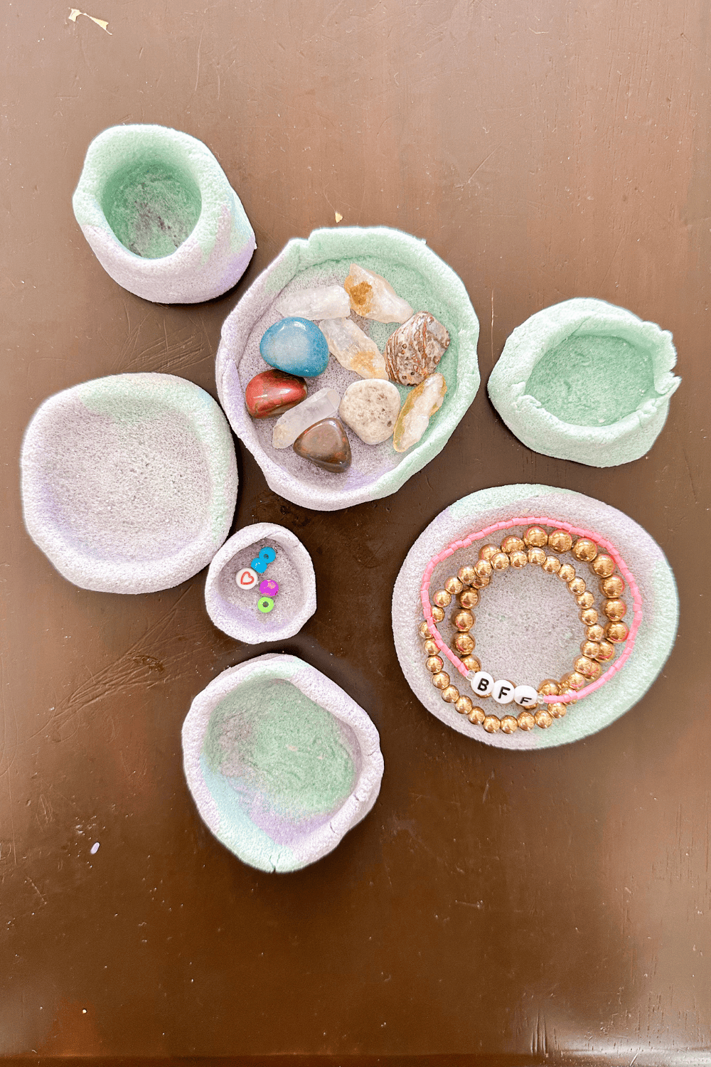 multiple two-tone blue and purple salt dough bowls. Some empty, one holding rocks, another holding bracelets.