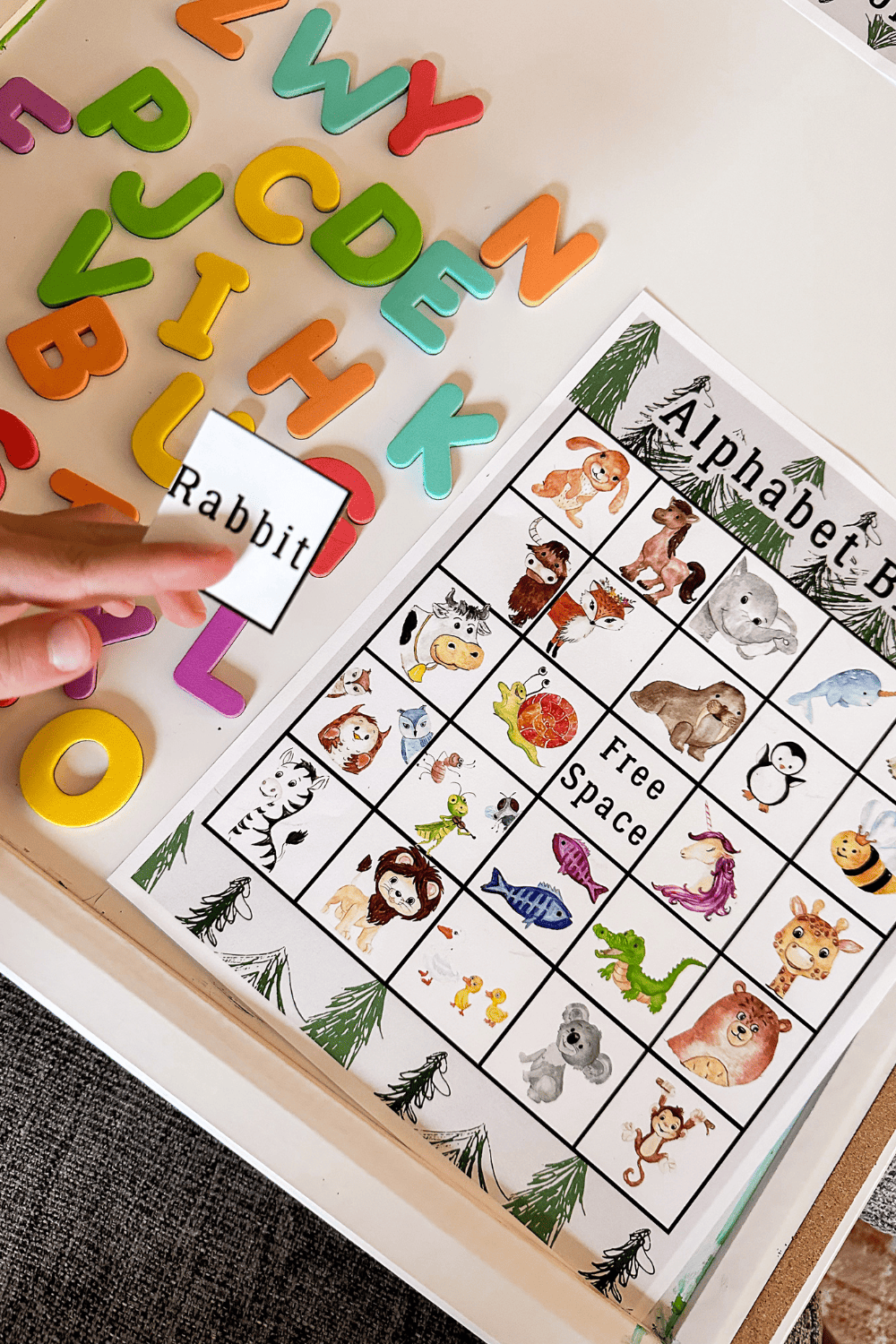 Alphabet bingo, a bingo board with a bunch of different animals. A hand holding a card that says Rabbit in the foreground