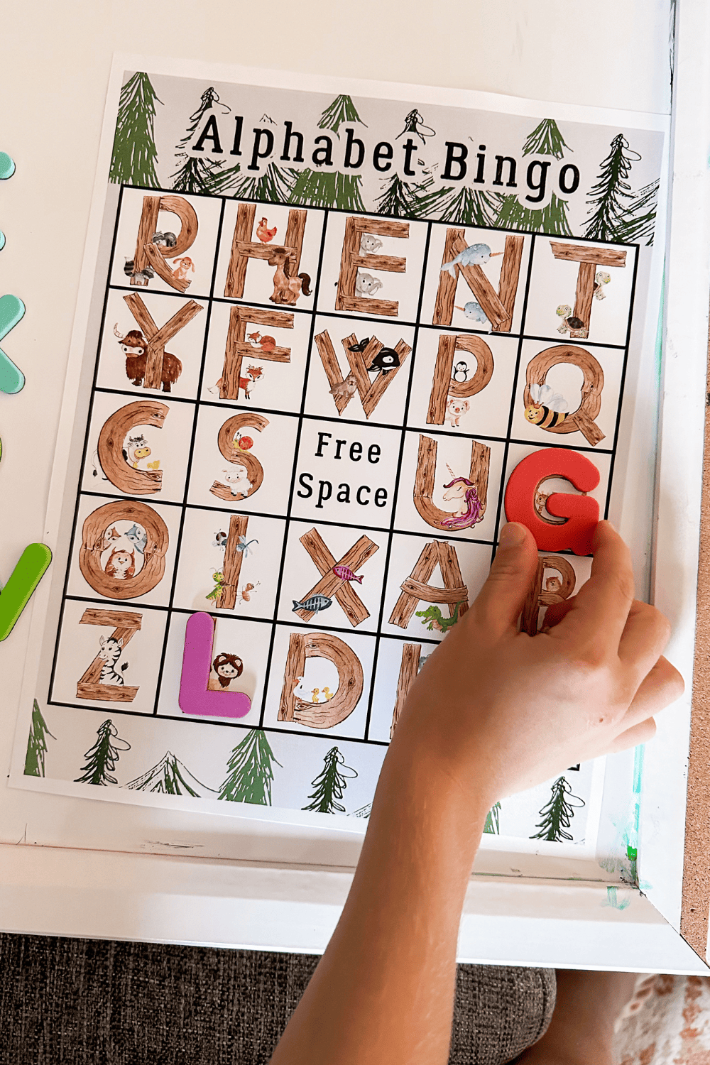 Alphabet bingo, a bingo board with a bunch of different letters. A hand placing a magnetic letter G on the board.