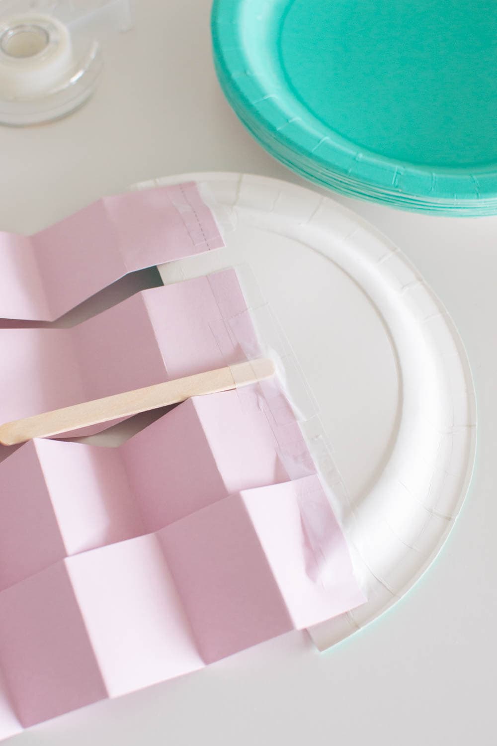 Adding folded strips of cardstock as well as a popsicle stick on the back of paper plate half