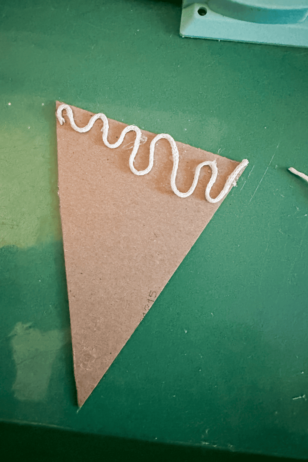 yarn squiggly line on the top of the cardboard triangle