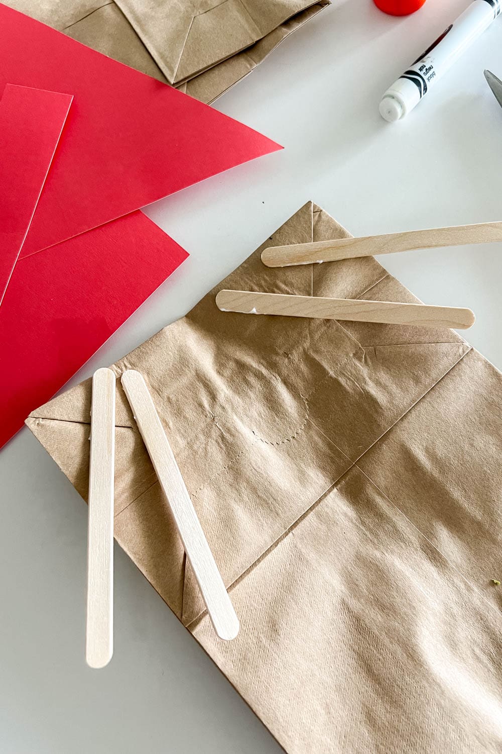 Gluing popsicle sticks on the paper bag