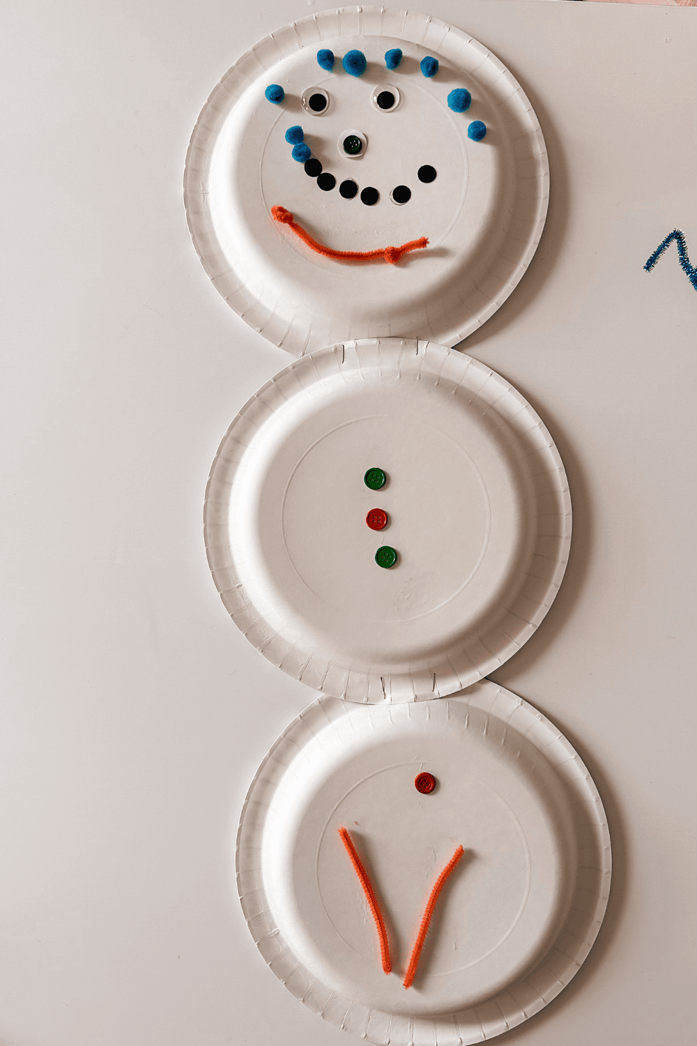 Paper plate snowman with pom pom hair and pipe cleaner beard.