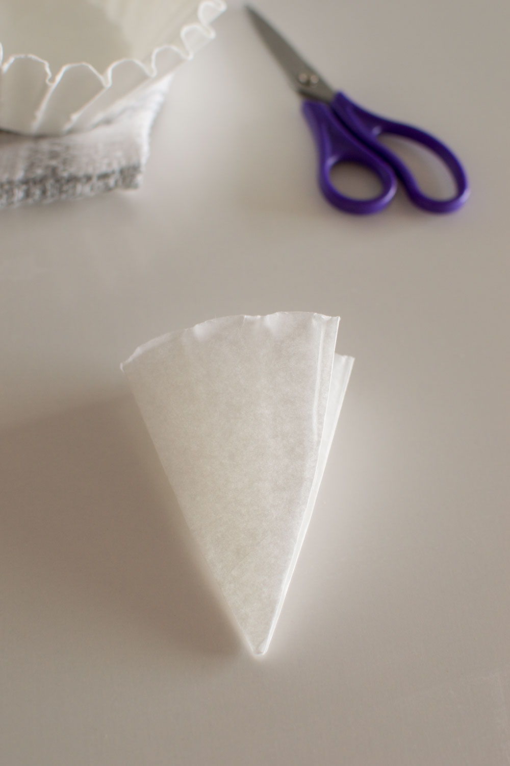 Folding white coffee filters to make coffee filter snowflakes