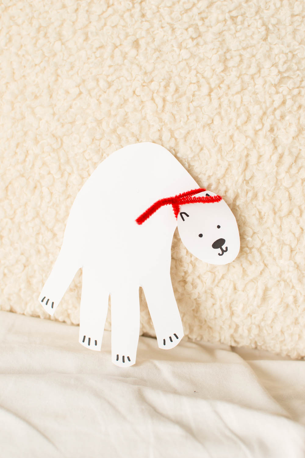 Cardstock polar bear leaning up against a beige pillow/backdrop