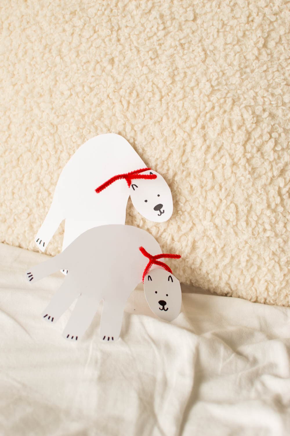 Cardstock polar bear leaning up against a beige pillow/backdrop